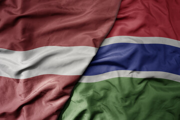 big waving national colorful flag of gambia and national flag of latvia.