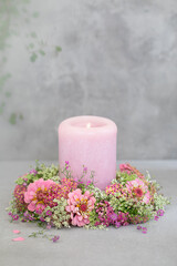 Różowa świeca otoczona wiankiem z letnich kwiatów. Cynie. - obrazy, fototapety, plakaty