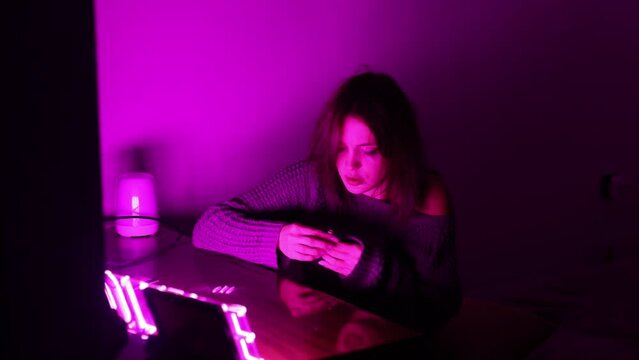 addicted woman in a den in a neon light sweater snorts drugs from the table. drug addiction