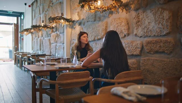 Friendly couple gossiping restaurant enjoying cozy atmosphere. Two women talking
