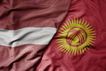 big waving national colorful flag of kyrgyzstan and national flag of latvia.