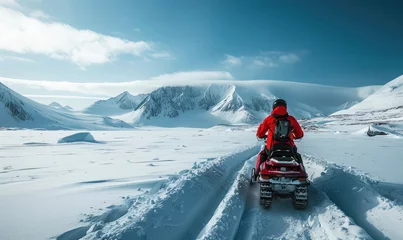 Fotobehang An adventurous person snowmobiling through a vast, snow-covered  mountains © piai