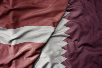 big waving national colorful flag of qatar and national flag of latvia.