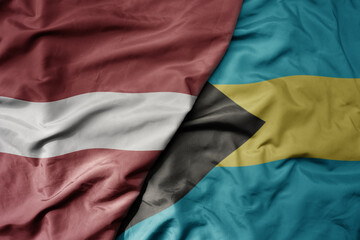 big waving national colorful flag of bahamas and national flag of latvia.