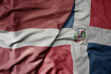 big waving national colorful flag of dominican republic and national flag of latvia.