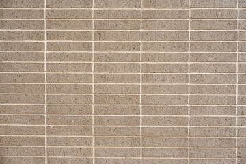 Wall covered with beige symmetrical and minimalistic tiles. Square and smooth material separated by light-colored grout lines. Concept of texture and pattern
