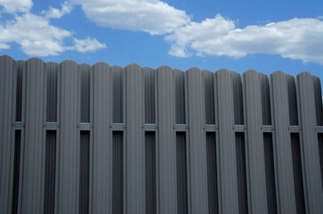 Modern metal picket fence on sky background