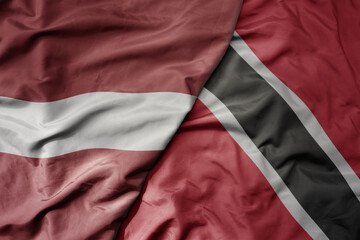 big waving national colorful flag of trinidad and tobago and national flag of latvia.
