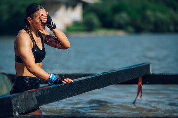 Woman athlete wiping the water off her face with a hand during OCR race