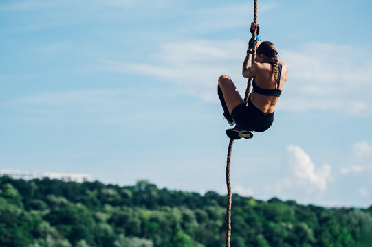 Female partake in an obstacle course race while preparing to climb the rope