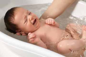 Fototapeta na wymiar Mother bathing her cute little baby in bathtub