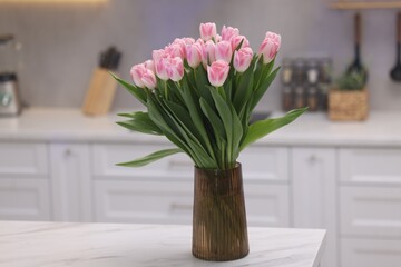 Beautiful bouquet of fresh pink tulips on table in kitchen
