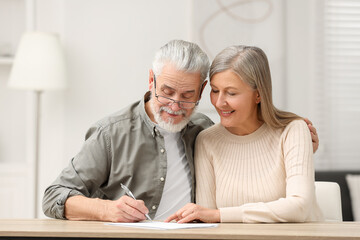 Senior couple signing Last Will and Testament indoors