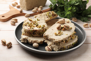 Pieces of tasty halva with pistachios on wooden table, closeup