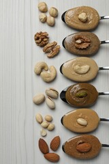 Tasty nut butters in spoons and raw nuts on white wooden table, flat lay