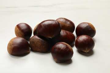Sweet fresh edible chestnuts on white table, closeup