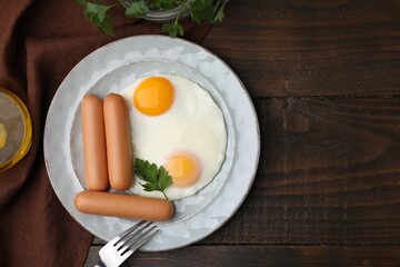 Delicious boiled sausages and fried eggs served on wooden table, flat lay. Space for text