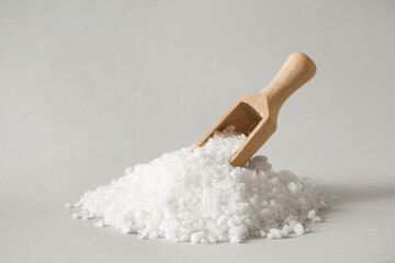 Organic salt and wooden scoop on light grey background
