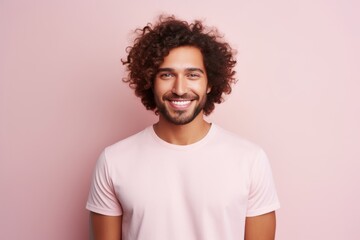 Fototapeta na wymiar Portrait of a handsome young african american man with curly hair smiling at camera while standing against pink background