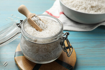 Raw basmati rice in jar on light blue wooden table, closeup