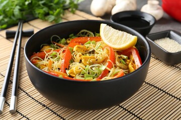 Stir-fry. Delicious cooked noodles with chicken and vegetables in bowl served on table, closeup