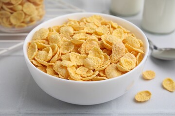 Tasty crispy corn flakes in bowl on white table, closeup. Breakfast cereal