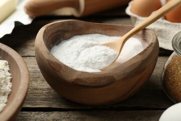 Baking powder and other ingredients for making dough on wooden table, closeup