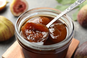 Jar of tasty sweet fig jam on table, closeup