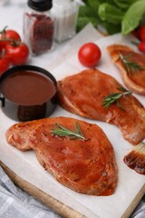 Raw marinated meat and rosemary on table, closeup