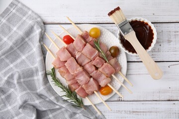 Skewers with pieces of raw meat, rosemary, tomatoes and marinade on rustic wooden table