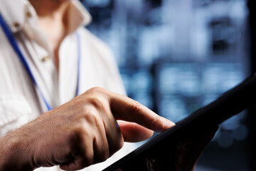 Qualified electrician inspects server rows in computer network security data center, ensuring...