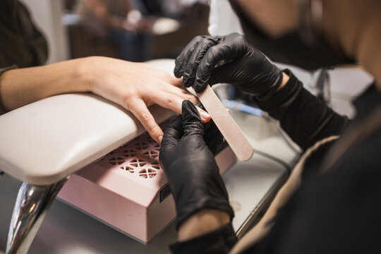 Professional manicurist shaping nails at a salon