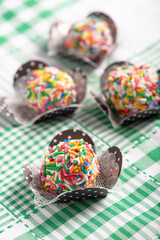 Brigadeiros, beautiful colorful sweets on a green and white tablecloth, selective focus.