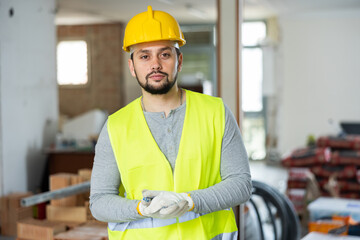Focused professional construction worker in uniform posing at indoor building site - Powered by Adobe