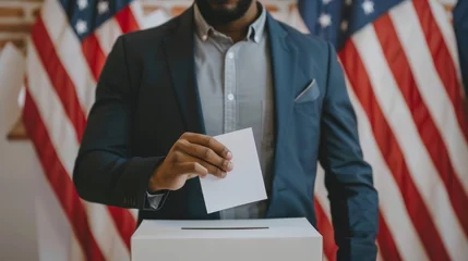 Deurstickers African American man voting in an election. Black voter casting ballot with US flags behind. Male hand placing ballot into voting box. Concept of democracy, presidential elections, freedom, diversity © Jafree