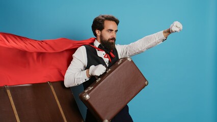 Hotel concierge acting like superhero with red cape, offering to help people with suitcases on...