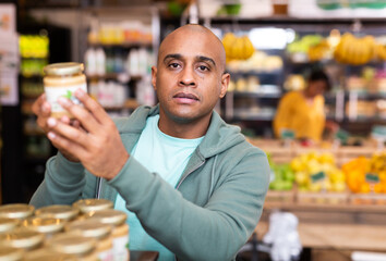 Adult positive man is choosing conserve in grocery supermarket
