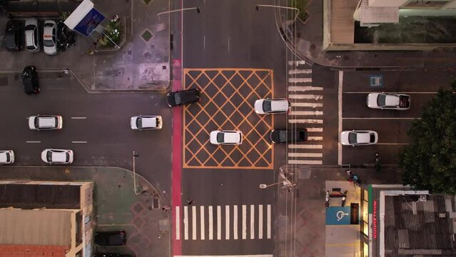 Cars passing by intersection with traffic safety paintings, traffic lights and pedestrian crossings, vertical view