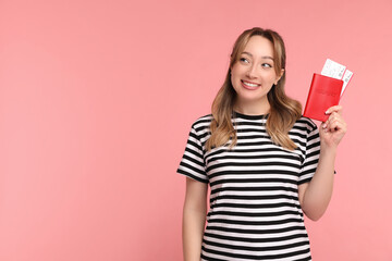 Happy young woman with passport and ticket on pink background, space for text