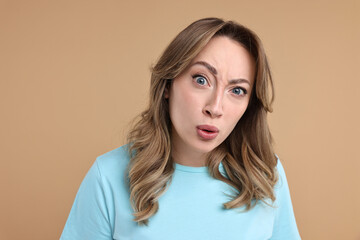 Obraz premium Portrait of surprised woman on beige background
