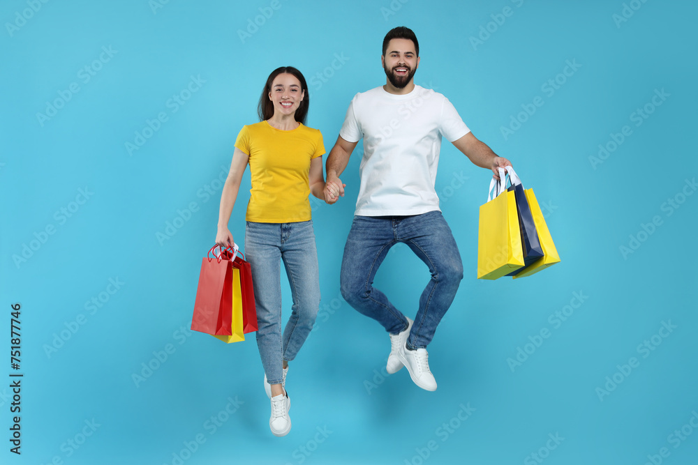 Sticker Happy couple with shopping bags jumping on light blue background