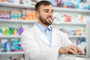 Fototapeta na wymiar Professional pharmacist working on laptop in modern drugstore