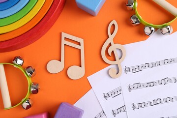 Naklejka premium Tools for creating baby songs. Flat lay composition with wooden notes and tambourines for kids on orange background