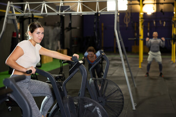 Fototapeta na wymiar Young athletic woman in sportswear training on exercise bike in gym
