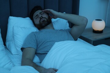 Man suffering from headache in bed at night