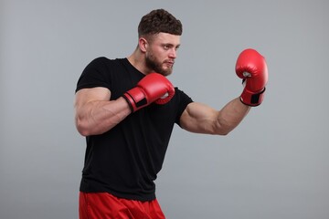 Man in boxing gloves fighting on grey background