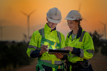 Team Engineers men and woman checking and inspecting on construction with sunset sky. people operation. Wind turbine for electrical of clean energy and environment. Industrial of sustainable.