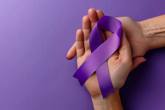 Purple ribbon on woman's hands - symbol of the fight against pancreatic cancer and epilepsy, isolated on purple empty background with space for text or inscriptions. Top view