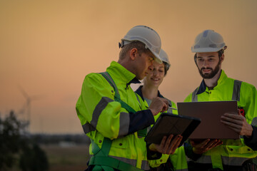 Team Engineers men and woman checking and inspecting on construction with sunset sky. people operation. Wind turbine for electrical of clean energy and environment. Industrial of sustainable.