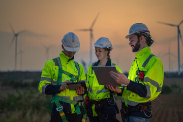 Team Engineers men and woman checking and inspecting on construction with sunset sky. people operation. Wind turbine for electrical of clean energy and environment. Industrial of sustainable.